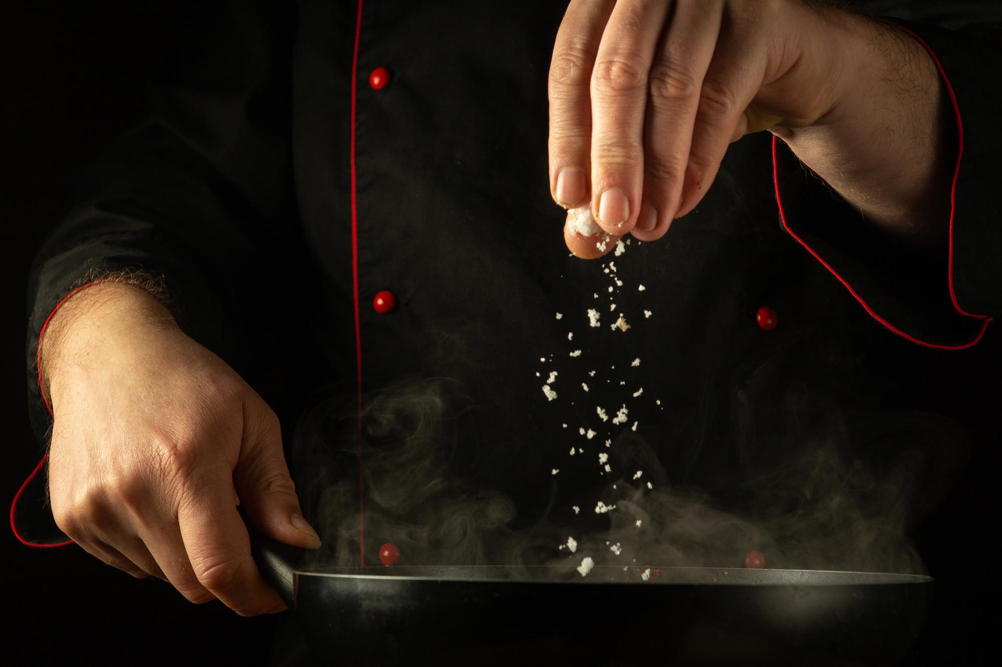 Close-up of chef's hands seasoning